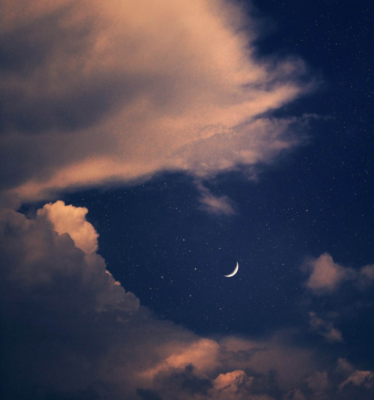 A serene night sky featuring a crescent moon surrounded by stars, partially framed by soft, illuminated clouds. The image evokes a sense of peace, wonder, and connection to the universe.